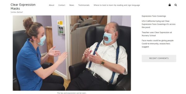 Website screen shot of Clear Mask website. Picture shows two people sat together wearing clear masks.
